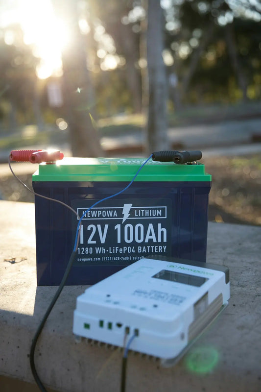 Ett svart och grönt 12V 100Ah litiumbatteri med en ansluten laddningsregulator.
