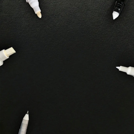 Vit markeringspenna med svart kapsel och spets, glansig finish.