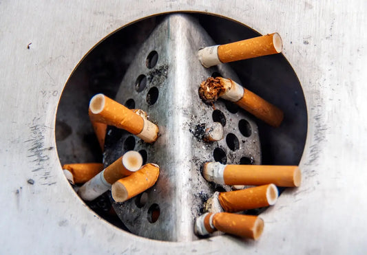 En utomhusbehållare av metall för cigarettavfall fylld med använda fimpar.