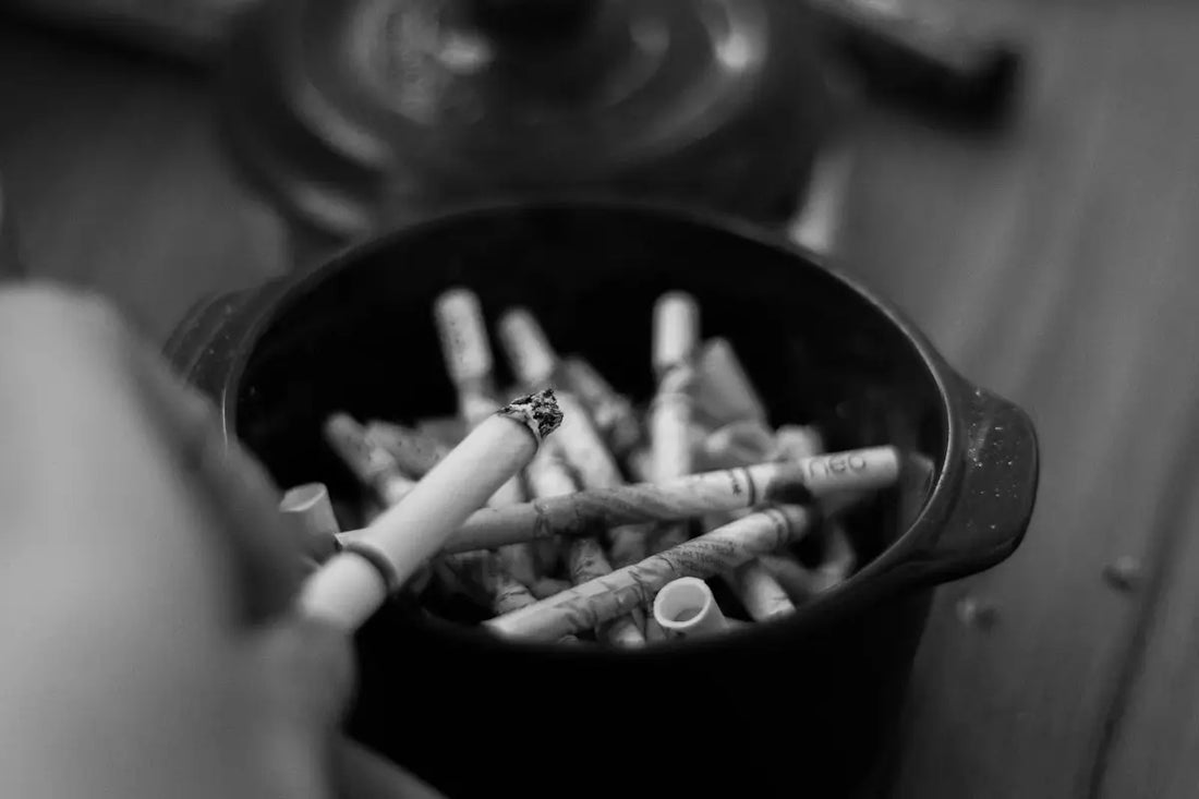 En svart askkopp fylld med ett stort antal cigarettfimpar.